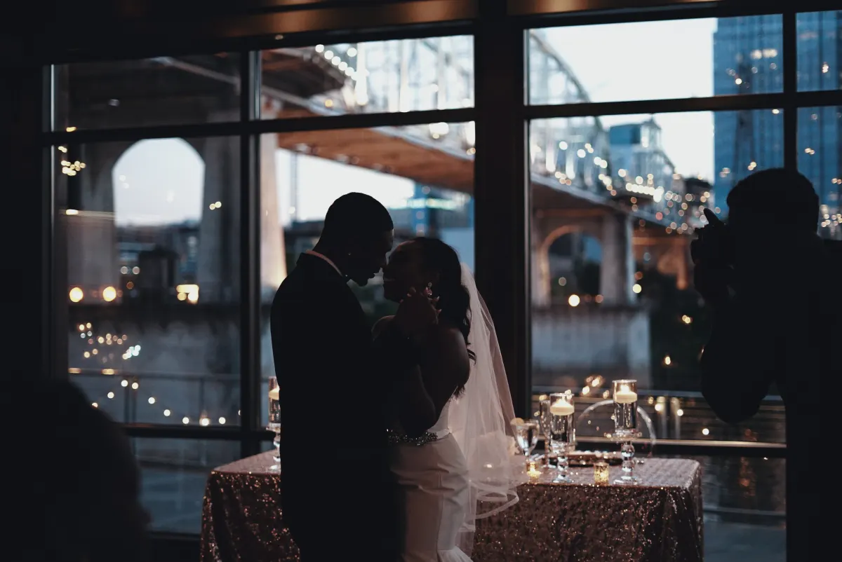 A couple dancing in silhouette against tall evening windows